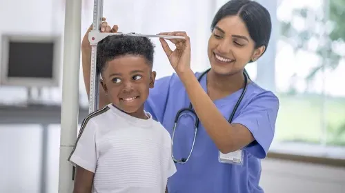 Medical assistant checking the height of pediatric patient